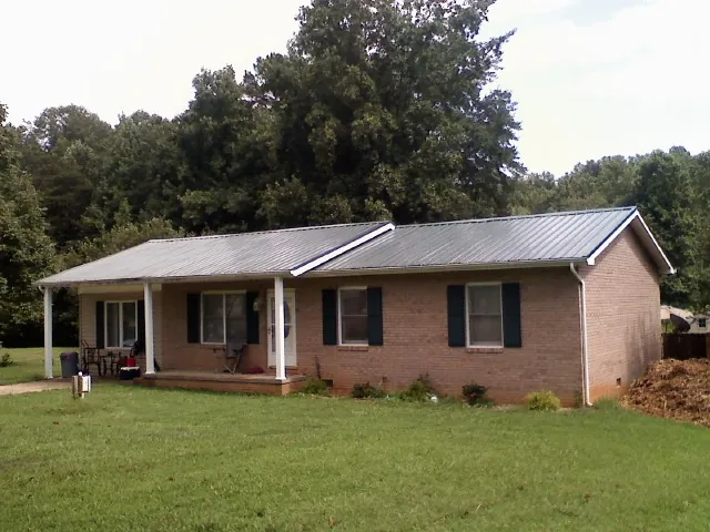 Gray metal roof on a brick ranch house with a side carport in Quincy